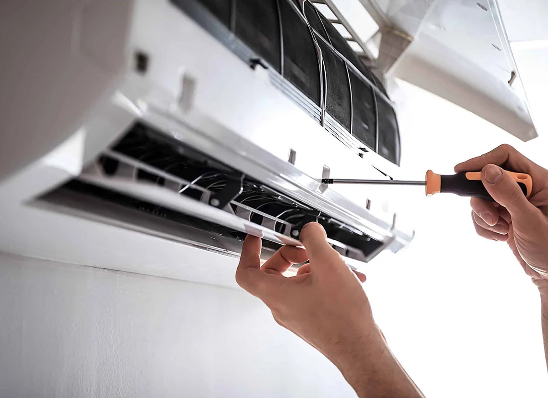 Technician using a screwdriver to repair a wall-mounted air conditioner