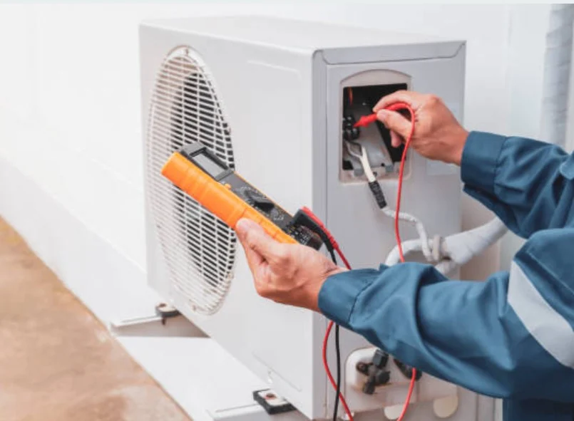 Technician testing an outdoor HVAC unit with a digital multimeter